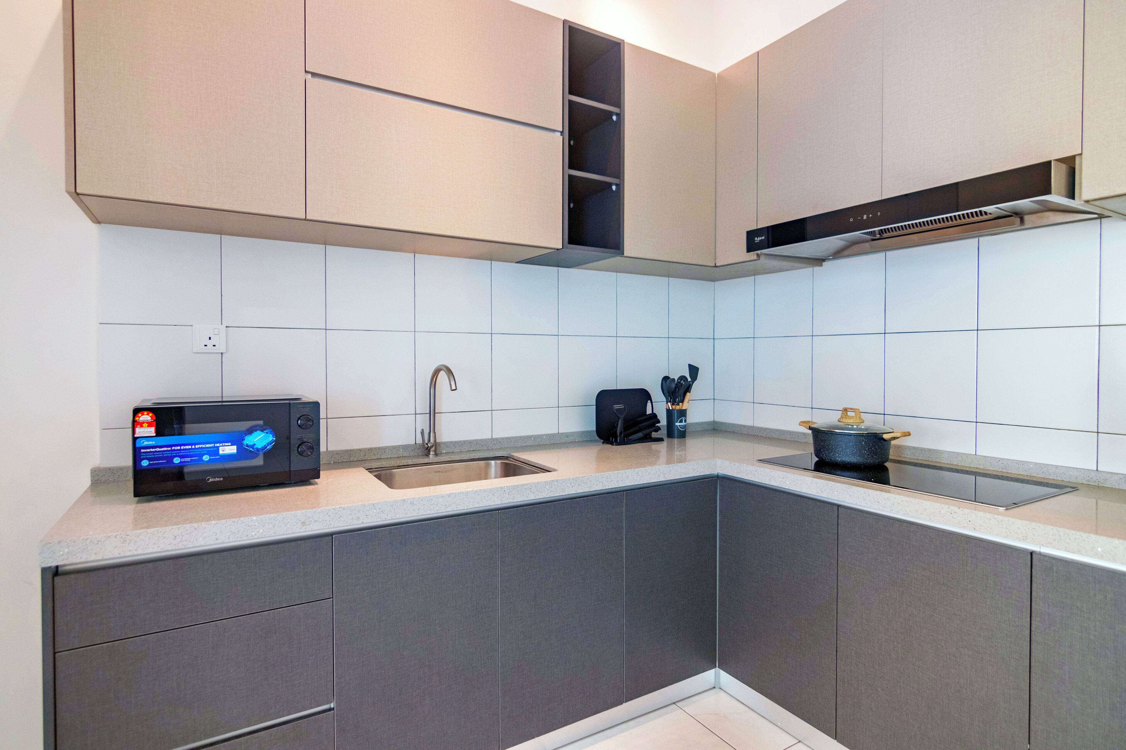 A modern kitchen with grey cabinets, a stainless steel sink, and a built-in oven.
