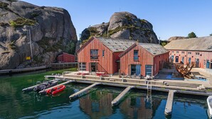 A waterfront building with a dock, boats, and rocky cliffs. - Awesome home in Søgne with WiFi (Søgne)