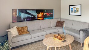 A modern living room with a grey patterned sofa, a round wooden coffee table, and abstract art on the wall. - Awesome home in Søgne with WiFi (Søgne)