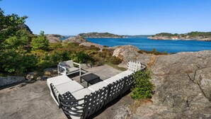 An outdoor seating area with a view of the sea, surrounded by rocks and greenery. - Awesome home in Søgne with WiFi (Søgne)