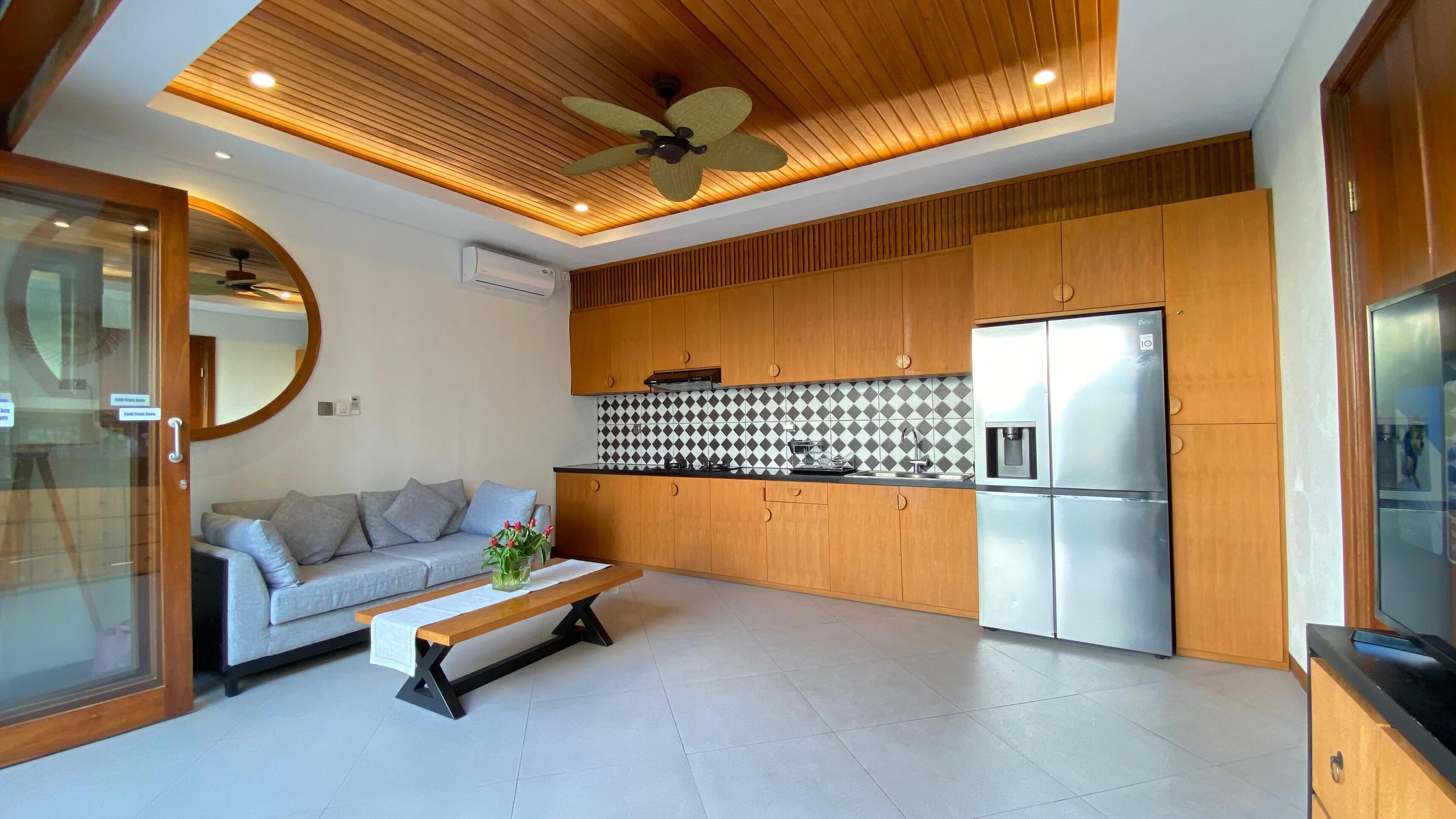 Una cucina moderna con mobili in legno, forno integrato e frigorifero in acciaio inossidabile.