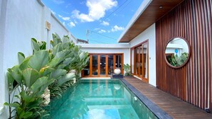 Ein modernes Haus mit Swimmingpool, Holzterrasse und großen Fenstern.