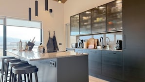 A modern kitchen with a large island, bar stools, and a view of the mountains. - Bakkar Luxuary Lodge (Grímsnes- og Grafningshreppur)