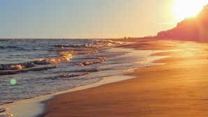 Ein Strand mit Wellen und einem Sonnenuntergang.