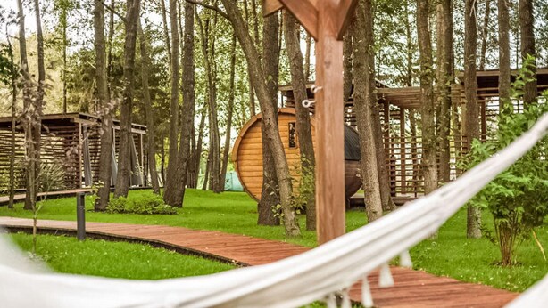 A wooden structure with a circular design, surrounded by trees and a grassy area. - Amazing home in Niechorze with sauna (Niechorze)