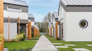 A modern residential building with a central pathway, wooden fences, and a well-maintained lawn. - Amazing home in Niechorze with sauna (Niechorze)