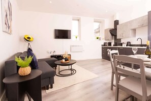 A modern living room with a sofa, a coffee table, and a dining area with a table and chairs. - City Getaway: Cosy 1Bed Apt in Hull Centre (Hull)