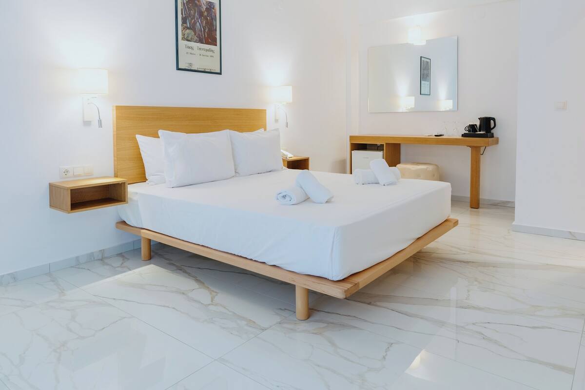 Ein modernes Hotelzimmer mit einem großen Bett, Nachttischen, einem Schreibtisch und einem Spiegel.