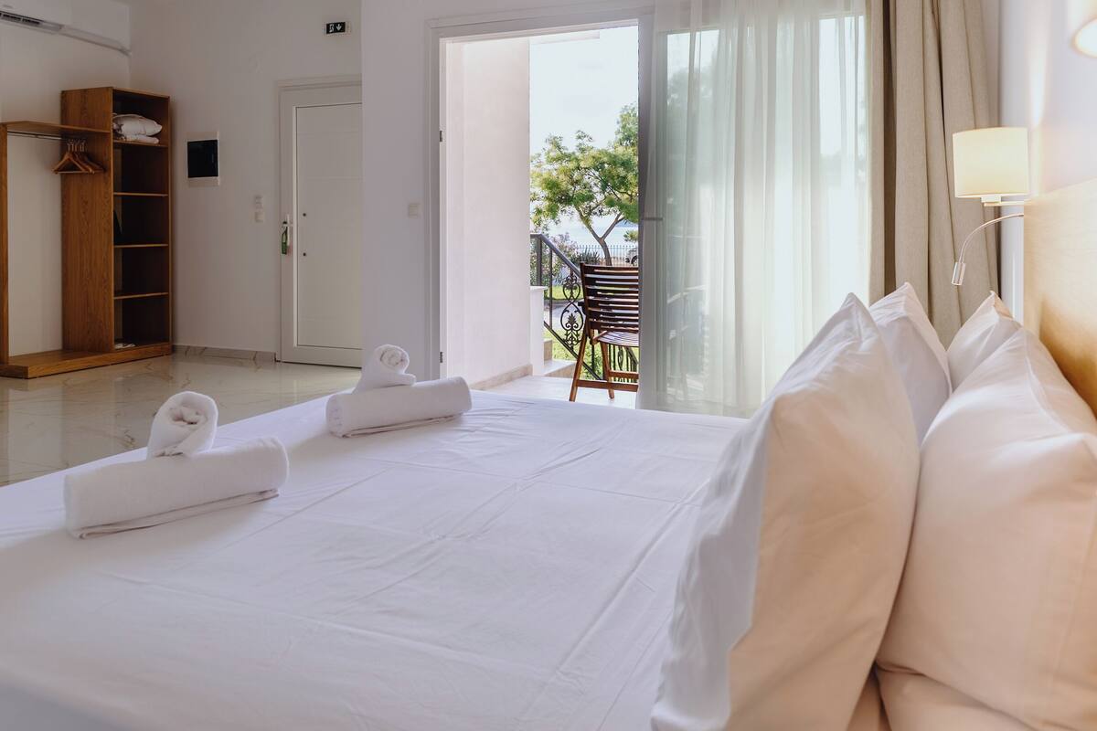 Ein Hotelzimmer mit einem großen Bett, einem Holzschrank und einem Balkon mit einem Stuhl.