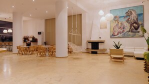 A spacious lobby with a high ceiling, modern furniture, and a large painting on the wall.