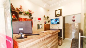 A hotel reception area with a wooden reception desk, a Samsung monitor, a television mounted on the wall, and a fire extinguisher. - Hotel Silver Star (Panipat)
