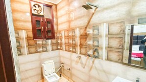 A bathroom with a toilet, a sink, a shower, and a mirror. - Hotel Silver Star (Panipat)