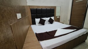 A neatly made bed with a dark headboard, a wooden bedside table, and a brown throw blanket. - Hotel Silver Star (Panipat)