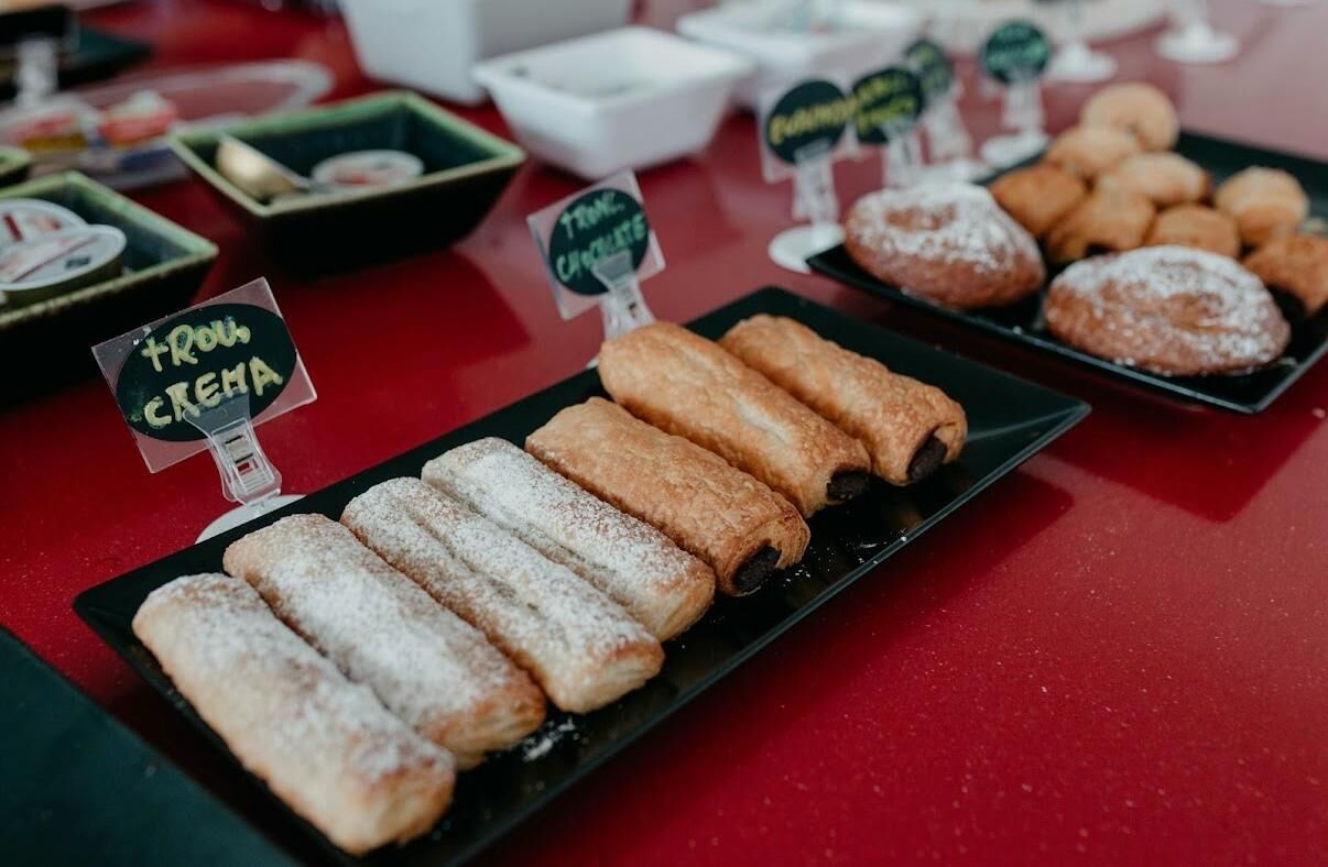 A display of various pastries on a table with signs indicating flavors like 'touc creme' and 'touc chocolat'.