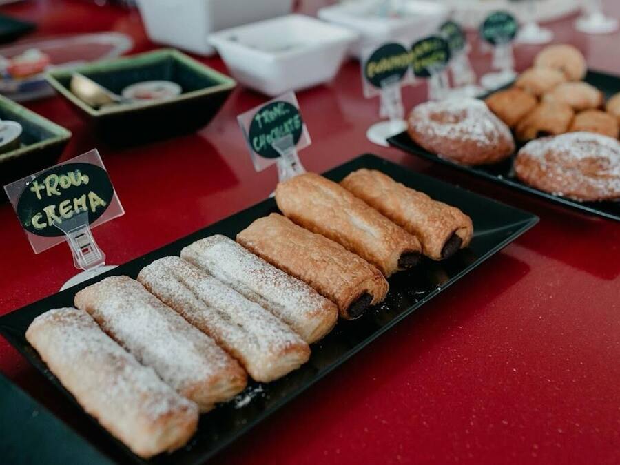 A display of various pastries on a table with signs indicating flavors like 'touc creme' and 'touc chocolat'.
