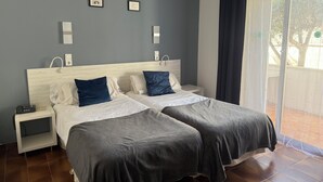 Un letto matrimoniale con due cuscini, un comodino e una finestra con tende.
