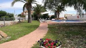 Un vialetto conduce a una zona piscina, con un'aiuola in primo piano.