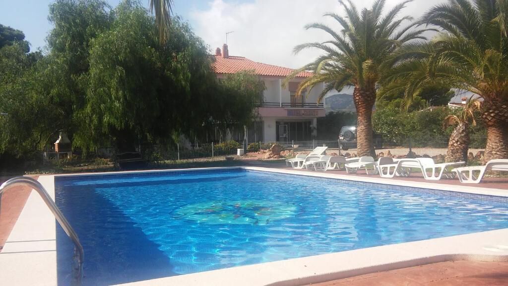 A swimming pool with lounge chairs and palm trees.