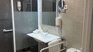 Een moderne badkamer met een douche, een wastafel met spiegel en een toilet.