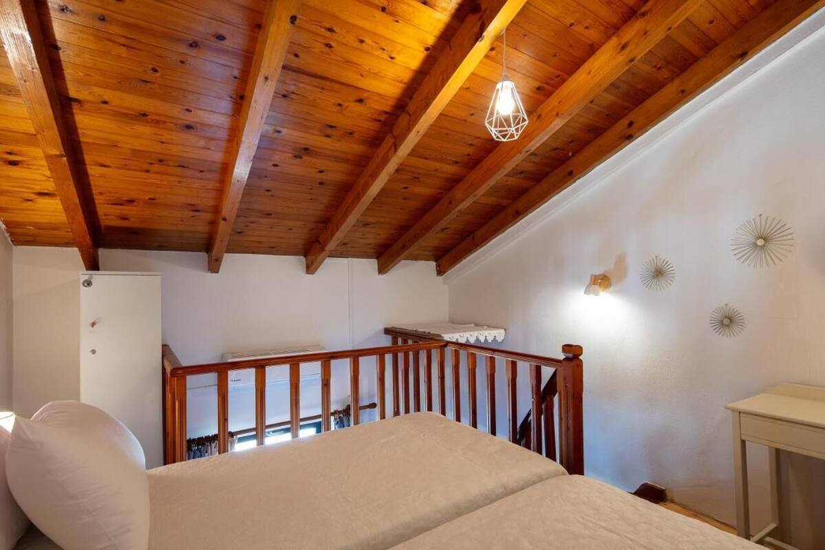 A bedroom with a wooden ceiling, a bed, a staircase, and a wall with decorative lights.