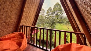 Ein Zimmer mit Holzboden, roter Geländer und Blick auf eine grüne Landschaft mit Bäumen.