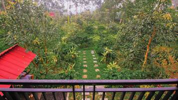 Un giardino con un sentiero, immerso nel verde e con una costruzione dal tetto rosso.
