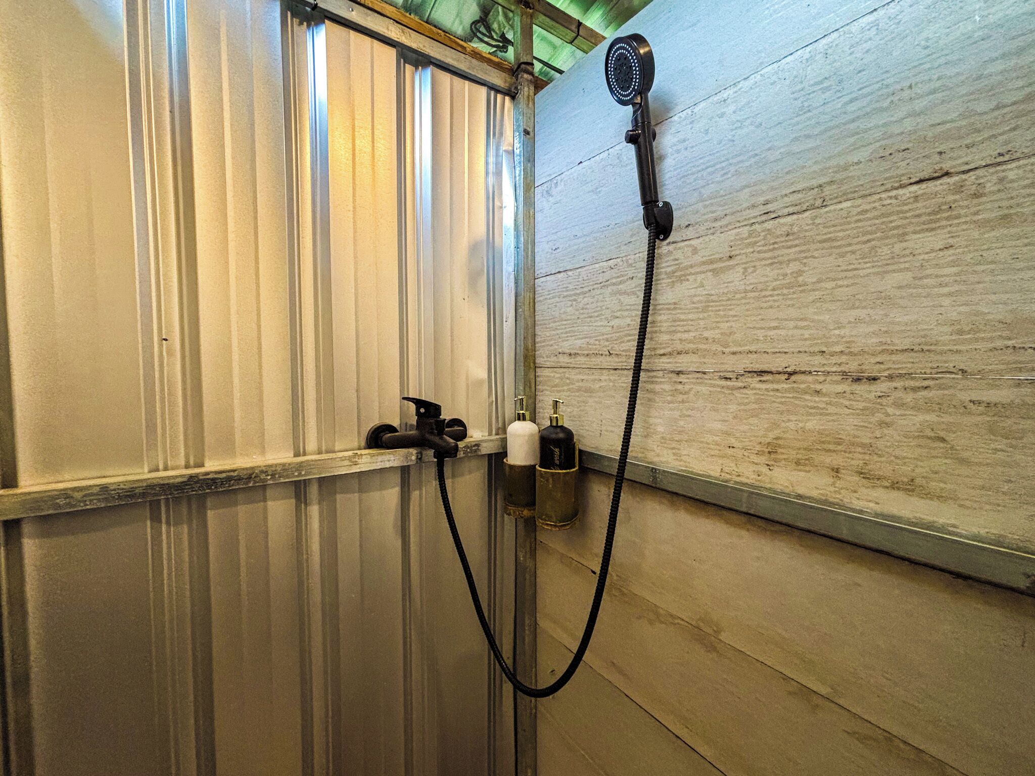 A bathroom with a shower, a towel rack, and a bottle of shampoo.