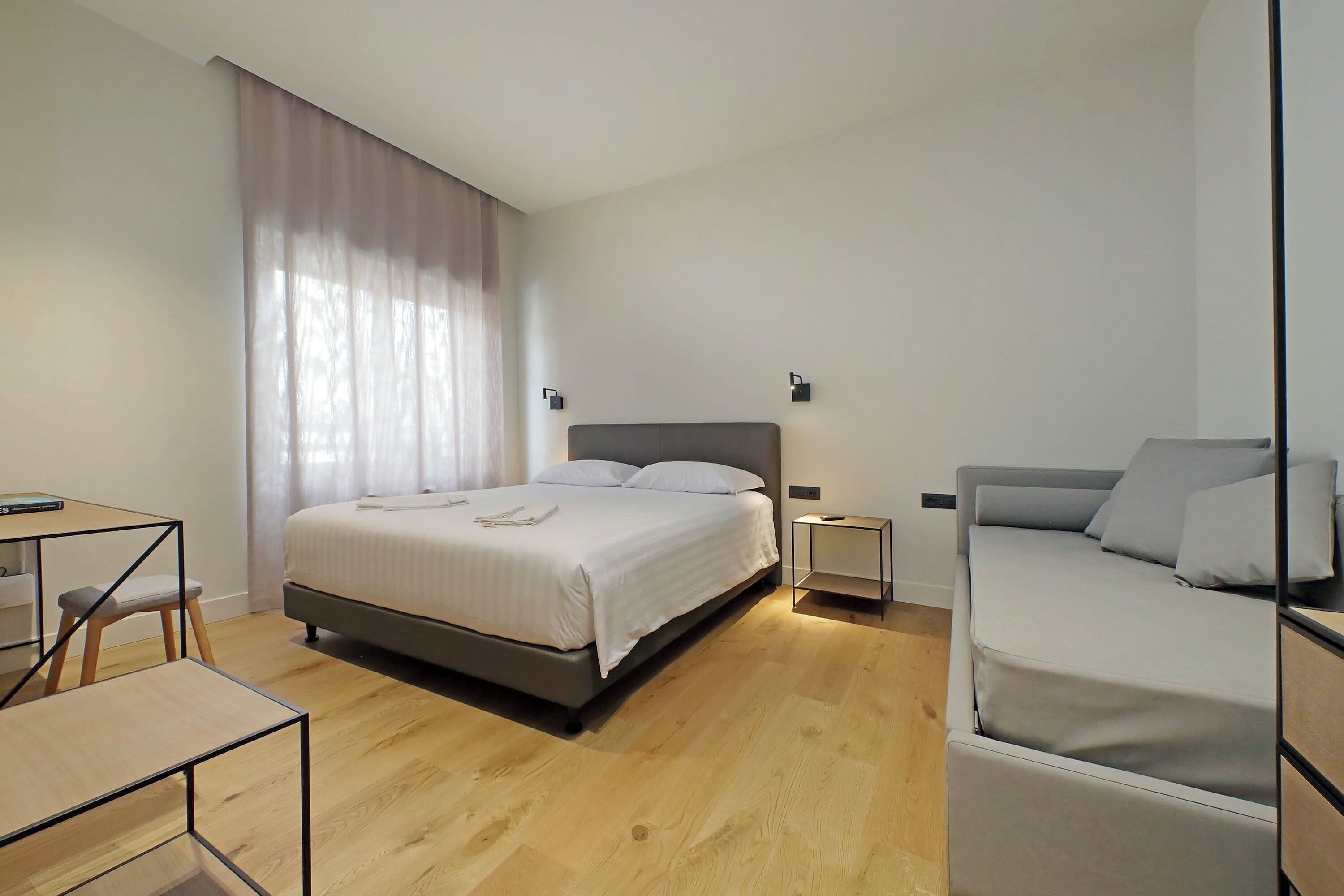 A modern bedroom with a large bed, a desk, and a chair.