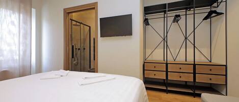 Une chambre d’hôtel comprenant un lit, une armoire en bois, un téléviseur et un espace douche.