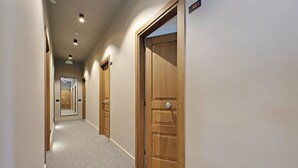 A hallway with wooden doors, carpeted floors, and recessed ceiling lights. - The Place Gallia (Rome)