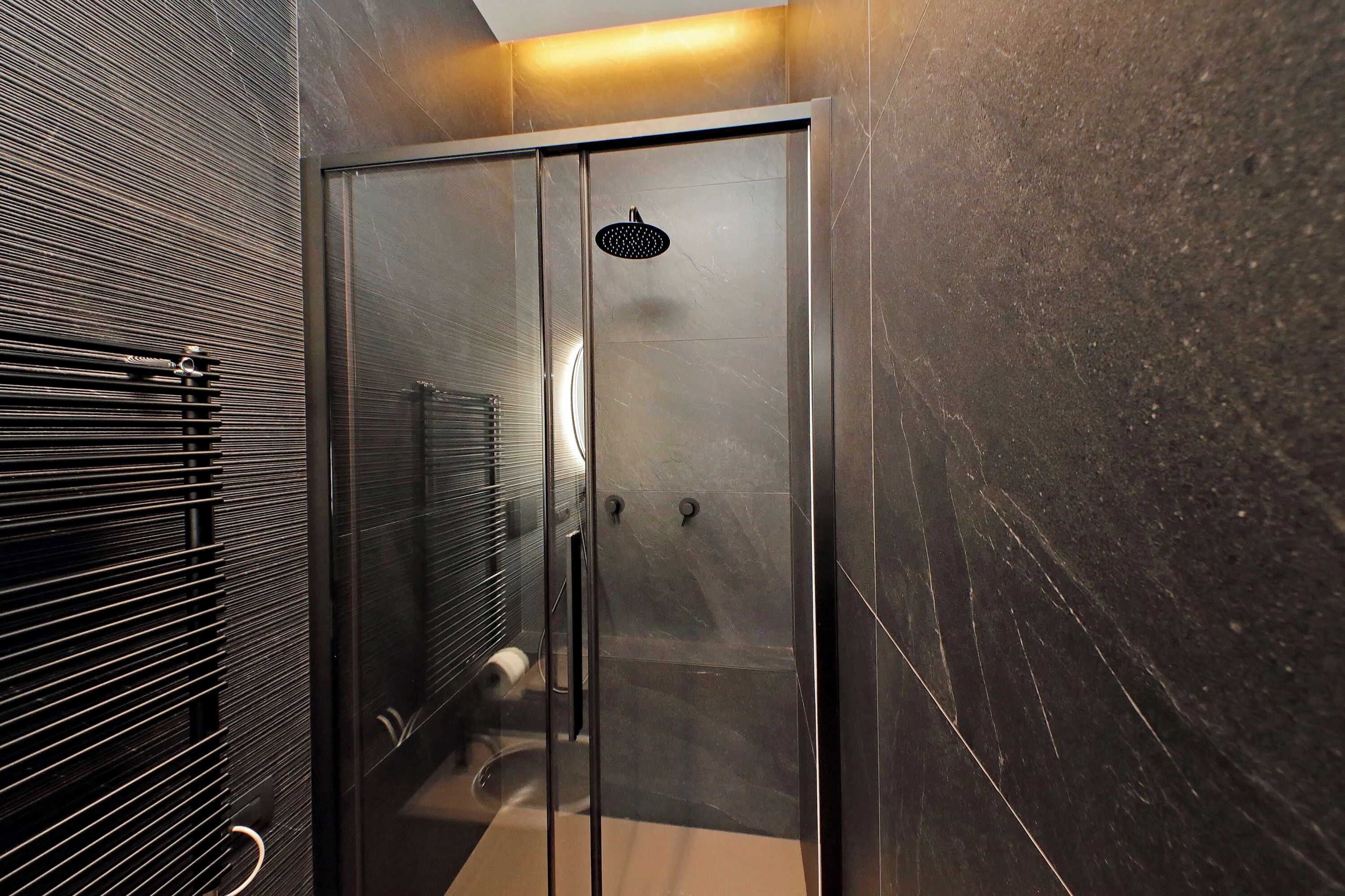 A modern bathroom with a glass-enclosed shower, a towel rack, and a toilet.