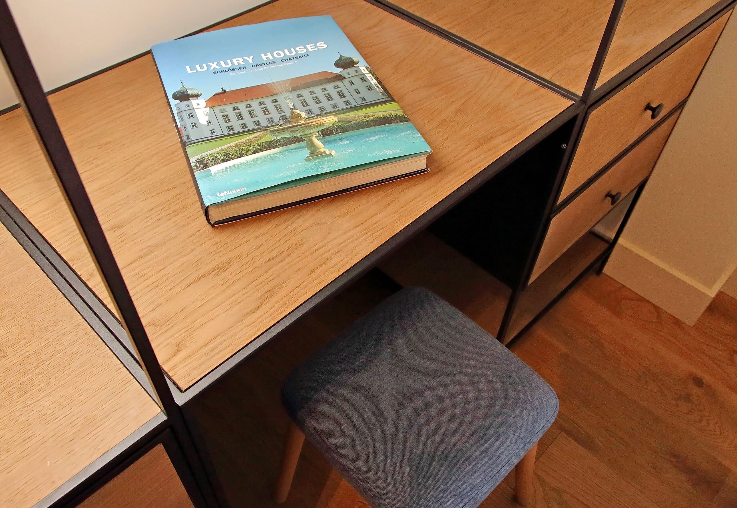 A book titled "Luxury Houses" on a wooden desk with a chair.