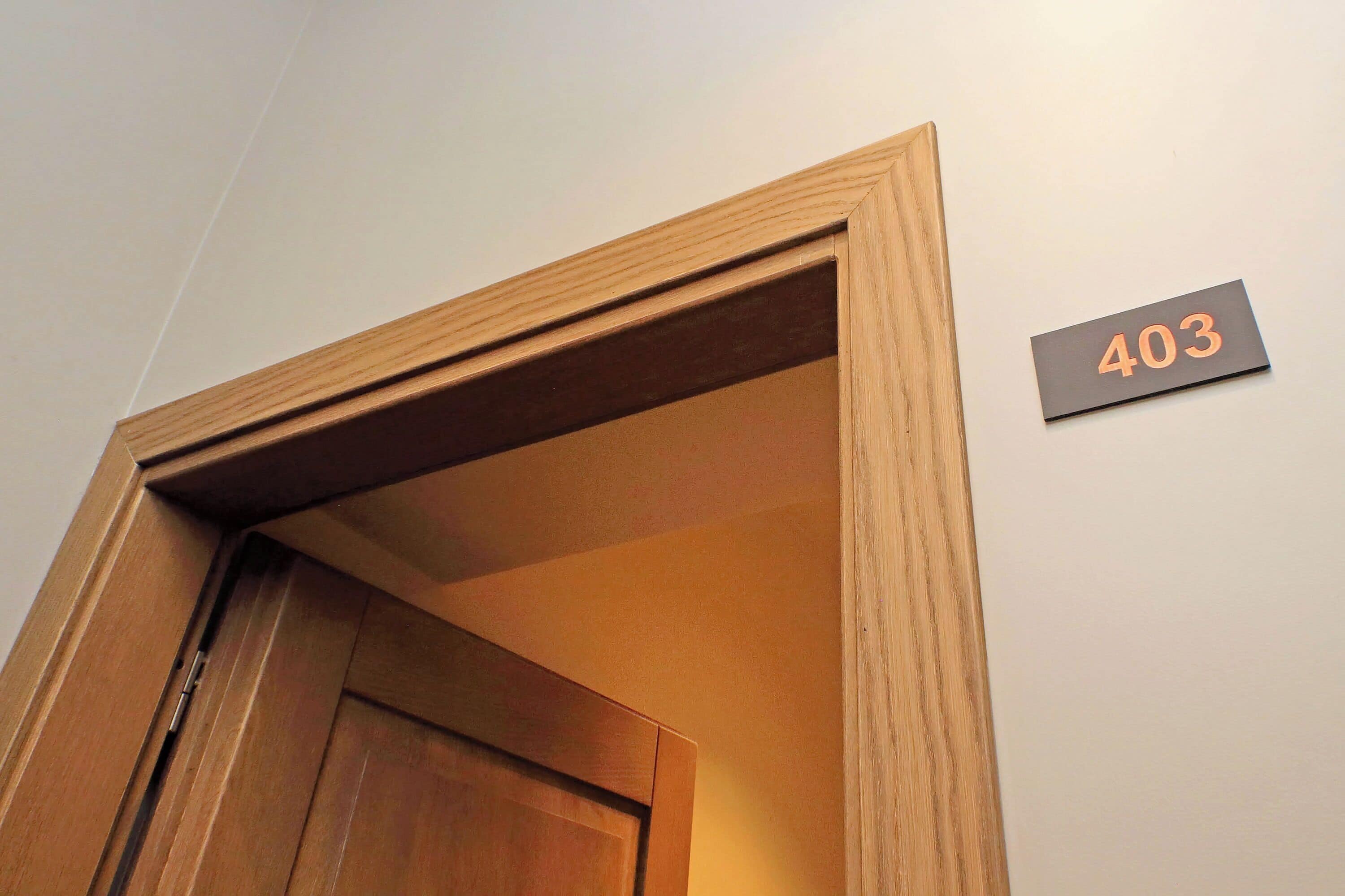 Un cadre de porte en bois avec une plaque numérotée « 403 » fixée au mur.
