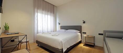 A modern bedroom with a bed, bedside tables, a desk, and a chair.