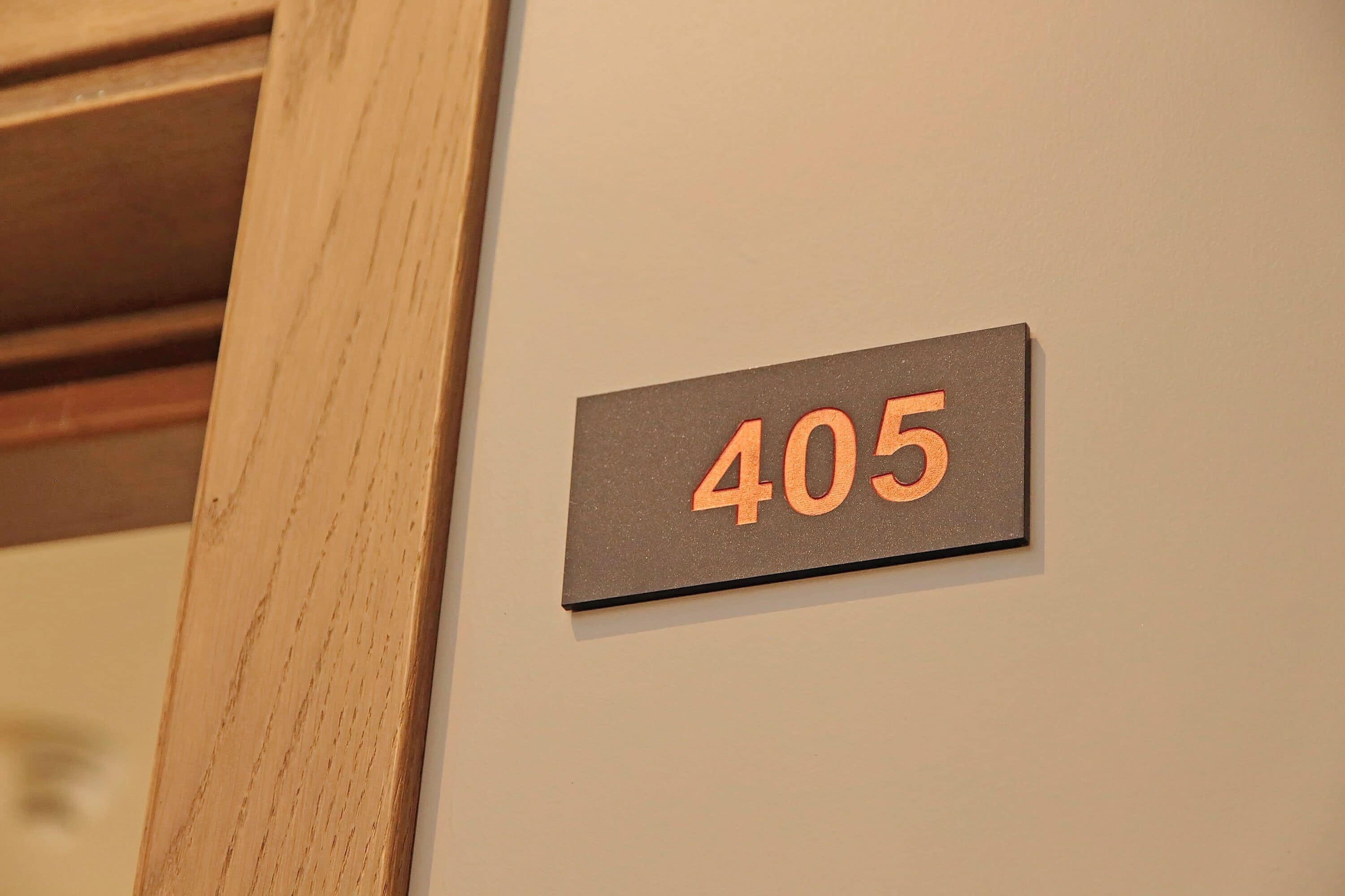 Een bord met kamer nummer 405 op een muur.