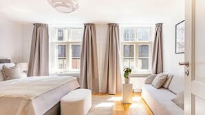 A modern bedroom with a bed, a sofa, a small table, and a potted plant. - Regent 15 - Bright 1 Bdr Apt right in the Centre of Copenhagen (København)
