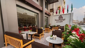 An outdoor seating area with wooden furniture and potted plants. - luluat alsafa apatments (Jeddah)