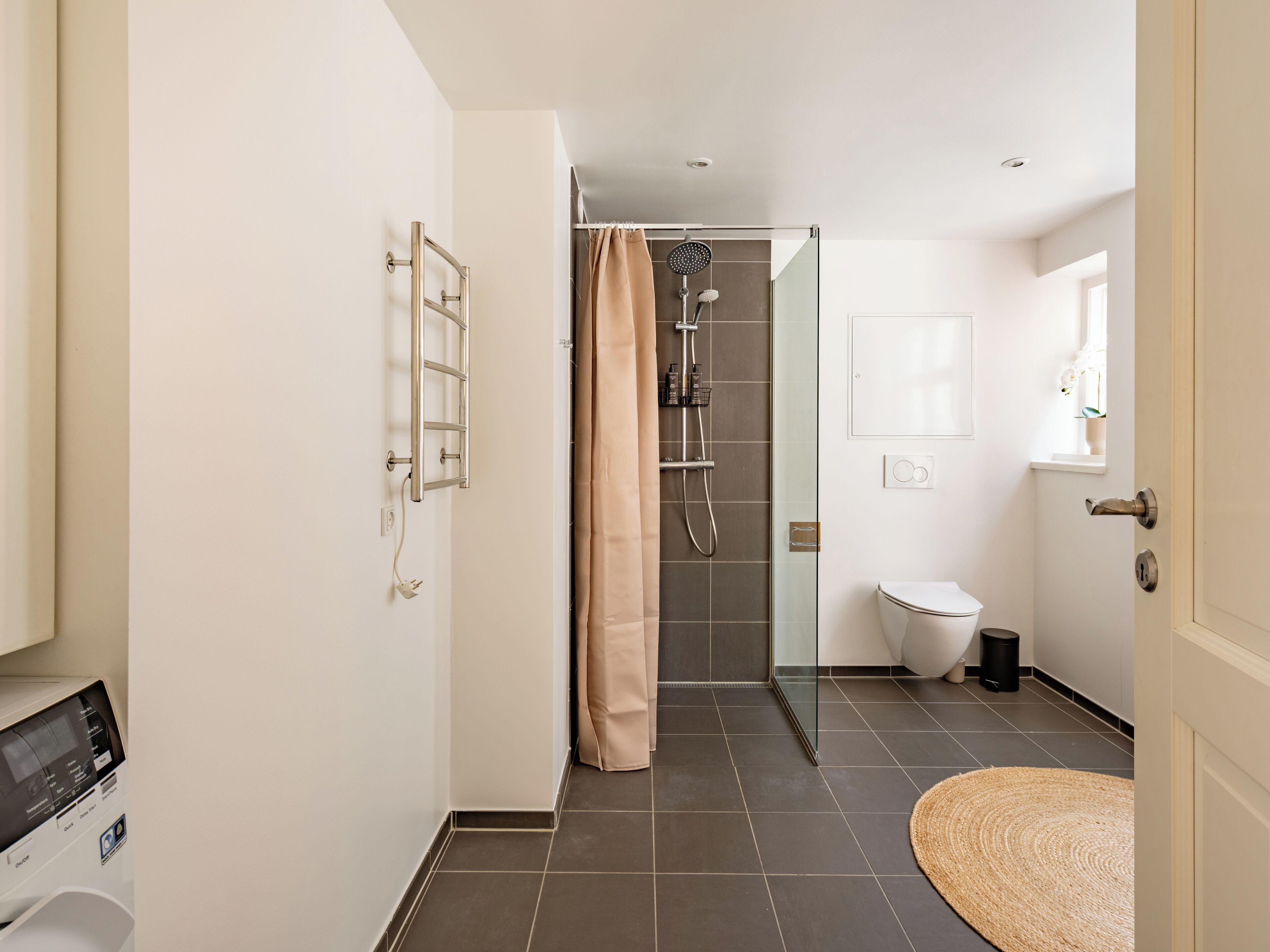 A modern bathroom with a shower, toilet, and a towel rack.