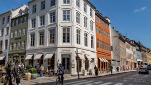 Ein Eckgebäude mit mehreren Läden, darunter ein Café und ein Restaurant.
