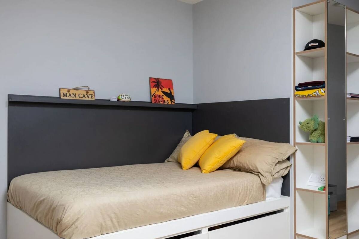 A bedroom with a bed, a wardrobe, and a shelf with items.
