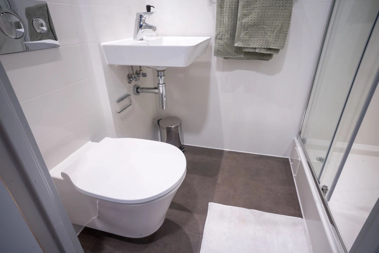 A modern bathroom with a white toilet, a sink, and a shower.