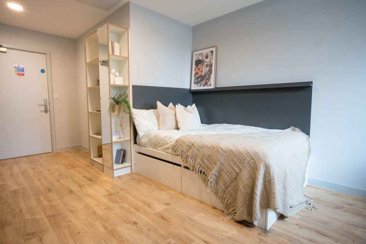 A bedroom with a bed, a built-in wardrobe, a bedside table, and a wall-mounted shelf.