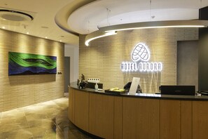 Uma receção de hotel com design moderno, um letreiro de neon e uma parede de tijolos.