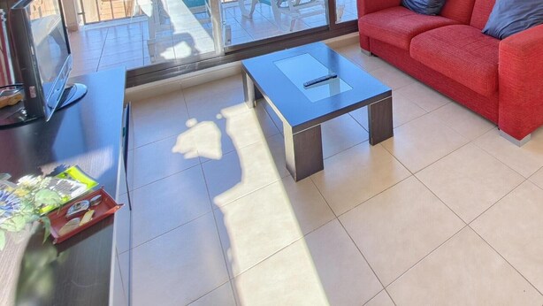 Un área de estar moderna con un sofá rojo, una mesa de centro de vidrio y una mesa de comedor con sillas.
