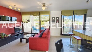 Una sala de estar moderna con un sofá rojo, un televisor y un comedor con una mesa y sillas.