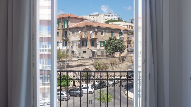Un balcón con vista a un paisaje urbano, un suelo con diseño y una puerta con cortinas.