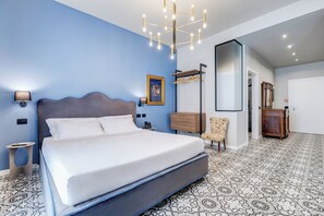 A modern bedroom with a large bed, a nightstand, a wall-mounted lamp, a dresser, a chair, and a mirror.