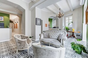 A spacious living area with a grand chandelier, a tufted sofa, and a marble coffee table.