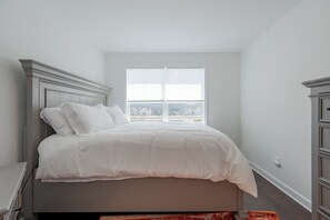 Un dormitorio con una cama, una ventana y vistas a edificios.