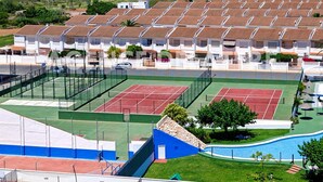 Asuinalue, jossa on useita valkoisia rakennuksia, tenniskenttä, uima-allas ja vihreä nurmialue.